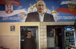 A man walks below a poster depicting Russia's President Vladimir Putin inside a newly-opened "Putin bar" in Novi Sad October 10, 2014. On Thursday, guns, tanks and planes will be back in Belgrade, now capital of Serbia, for a Liberation Day parade held four days early to accommodate the guest of honour -- Russian President Vladimir Putin, en route to a summit in Milan. Liberation Day marks the Nazi retreat across the River Sava on October 20, 1944, leaving the capital to the Red Army and Yugslav Partisan guerillas, and has been commemorated by memorials rather than military parades after Yugoslavia split with Josef Stalin's Soviet Union in 1948. It is a gesture with huge symbolism in a Cold-War-style East-West split over Ukraine that has forced Serbia, politically indebted to Russia but seeing its economic future with the European Union, into a delicate balancing act.   Picture taken October 10, 2014. TO GO WITH STORY SERBIA-RUSSIA/EU   REUTERS/Marko Djurica (SERBIA - Tags: POLITICS MILITARY BUSINESS) - RTR4A2LM