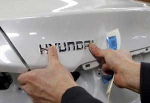A worker fixes the Hyundai logo on a vehicle at a plant of Hyundai Motor in Asan, south of Seoul